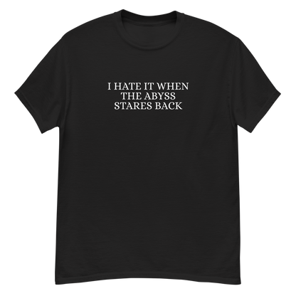"I hate it when the abyss stares back" printed on a black unisex classic tee laying on a flat surface