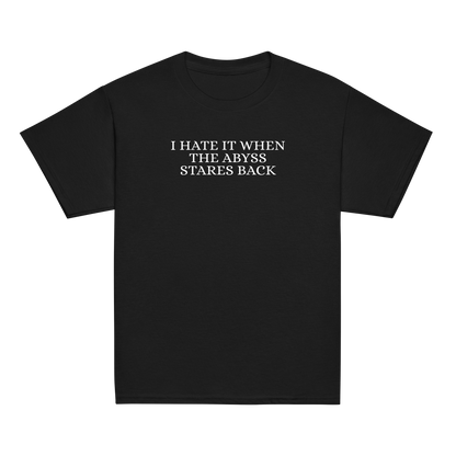 "I hate it when the abyss stares back" printed on a black youth classic tee laying on a flat surface