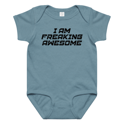 "I Am Freaking Awesome" printed on a vintage indigo baby jersey bodysuit laying on a flat surface amongst other clothes