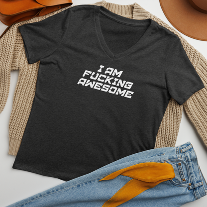 "I Am Fucking Awesome" printed on a dark grey heather women's relaxed v-neck t-shirt laying on a flat surface amongst other clothes