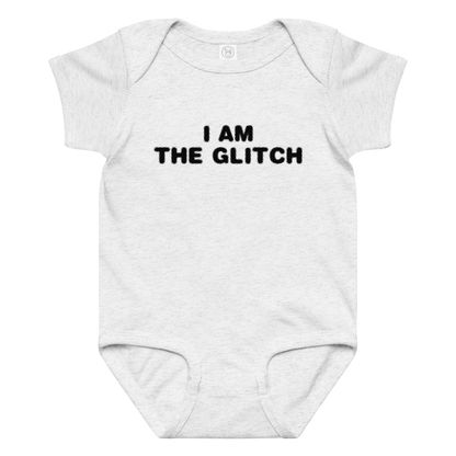 "I am the glitch" printed on a ash baby jersey bodysuit laying on a flat surface amongst other clothes
