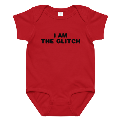 "I am the glitch" printed on a red baby jersey bodysuit laying on a flat surface amongst other clothes