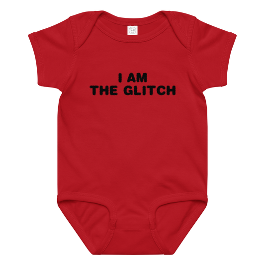 "I am the glitch" printed on a red baby jersey bodysuit laying on a flat surface amongst other clothes