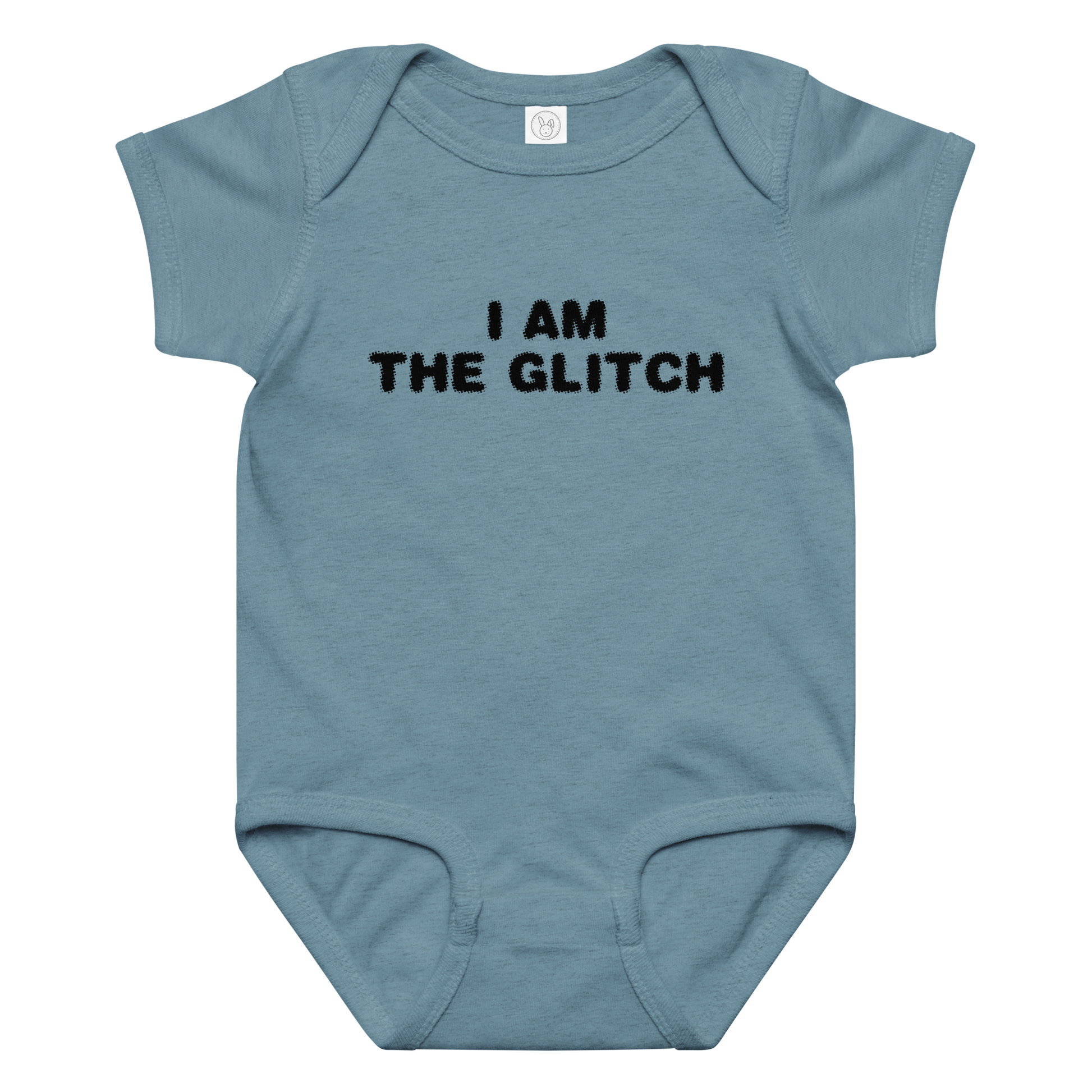 "I am the glitch" printed on a vintage indigo baby jersey bodysuit laying on a flat surface amongst other clothes