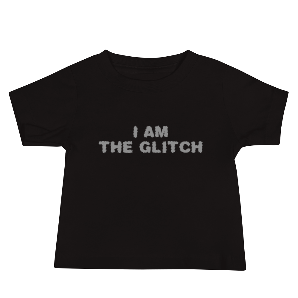 "I am the glitch" printed on a black baby jersey short sleeve tee laying on a flat surface