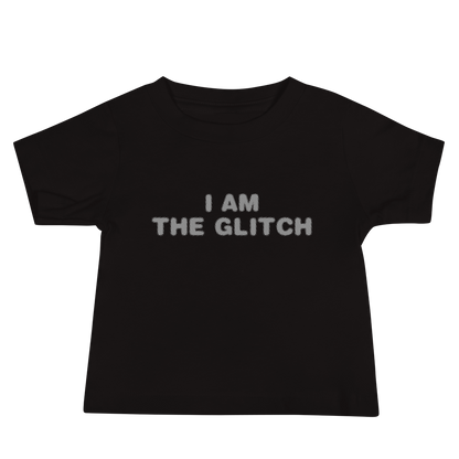 "I am the glitch" printed on a black baby jersey short sleeve tee laying on a flat surface