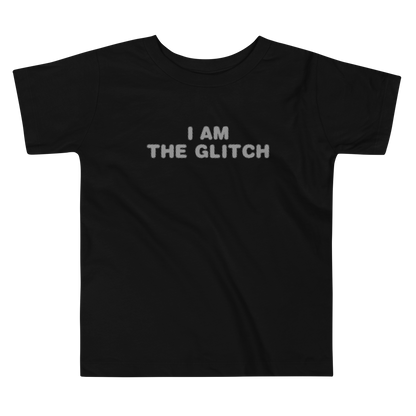 "I am the glitch" printed on a black toddler short sleeve tee laying on a flat surface