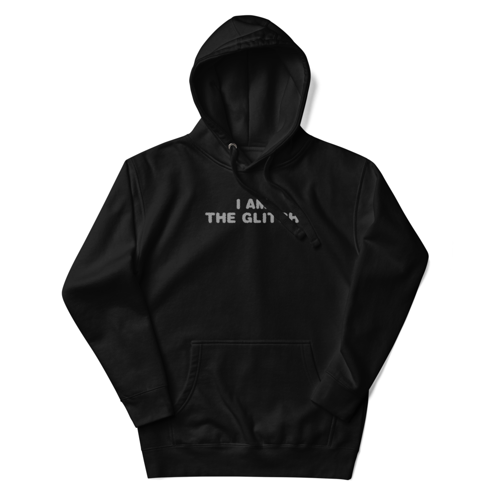 "I am the glitch" printed on a black unisex hoodie laying on a flat surface with the hood up