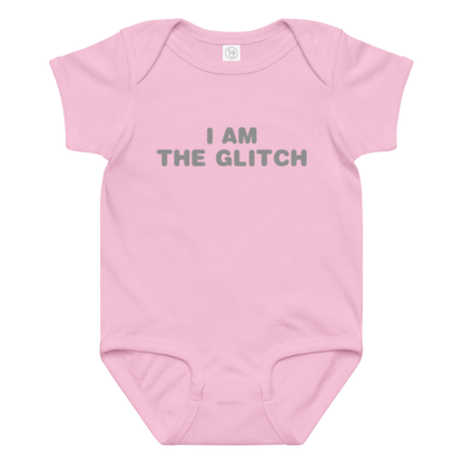 "I am the glitch" printed on a pink baby jersey bodysuit laying on a flat surface amongst other clothes