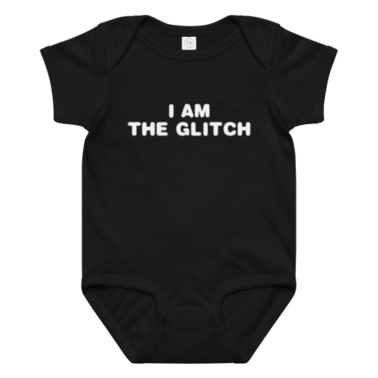 "I am the glitch" printed on a black baby jersey bodysuit laying on a flat surface amongst other clothes