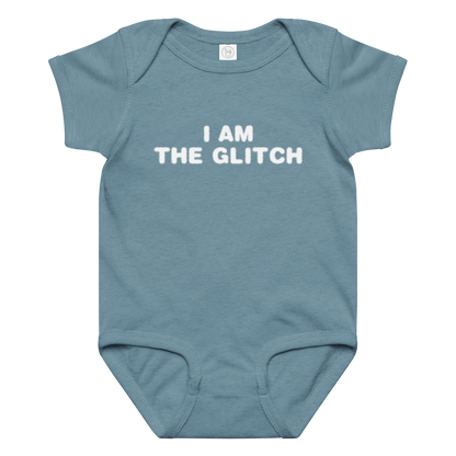"I am the glitch" printed on a vintage indigo baby jersey bodysuit laying on a flat surface amongst other clothes