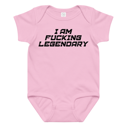 "I Am Fucking Legendary" printed on a pink baby jersey bodysuit laying on a flat surface amongst other clothes