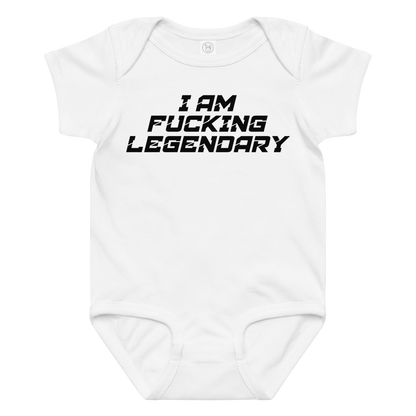 "I Am Fucking Legendary" printed on a white baby jersey bodysuit laying on a flat surface amongst other clothes