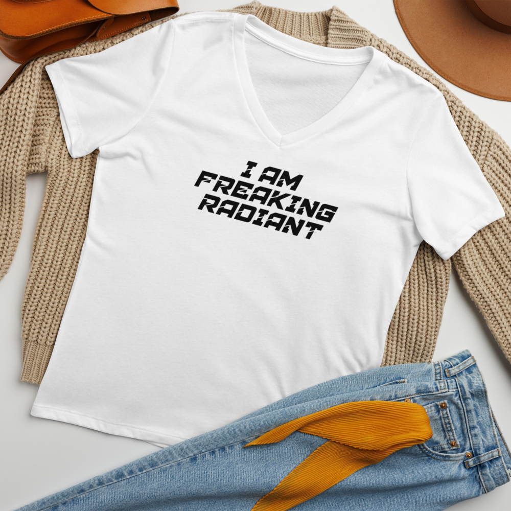 "I Am Freaking Radiant" printed on a solid white blend women's relaxed v-neck t-shirt laying on a flat surface amongst other clothes