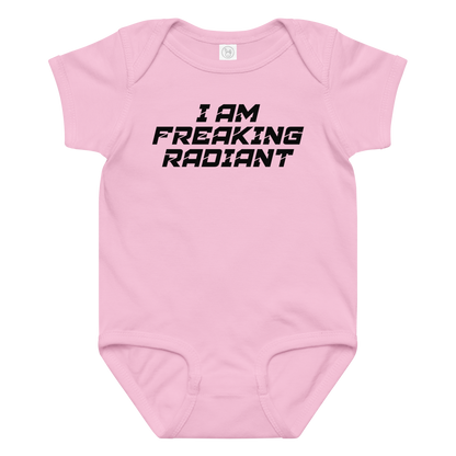 "I Am Freaking Radiant" printed on a pink baby jersey bodysuit laying on a flat surface amongst other clothes