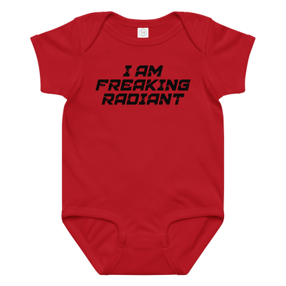 "I Am Freaking Radiant" printed on a red baby jersey bodysuit laying on a flat surface amongst other clothes