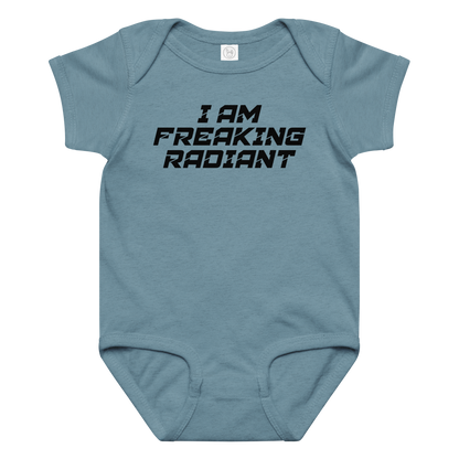 "I Am Freaking Radiant" printed on a vintage indigo baby jersey bodysuit laying on a flat surface amongst other clothes