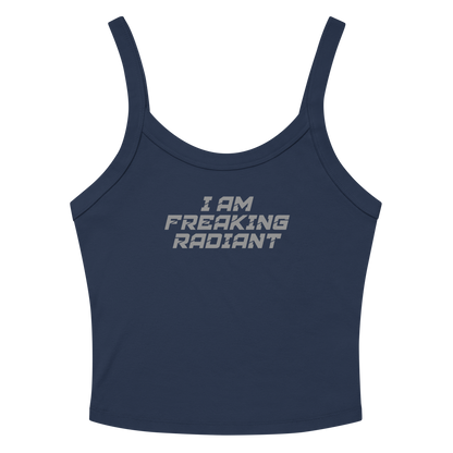 "I Am Freaking Radiant" printed on a solid navy blend women's micro-rib tanktop laying on a flat surface amongst sunglasses and shorts