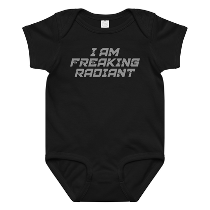 "I Am Freaking Radiant" printed on a black baby jersey bodysuit laying on a flat surface amongst other clothes