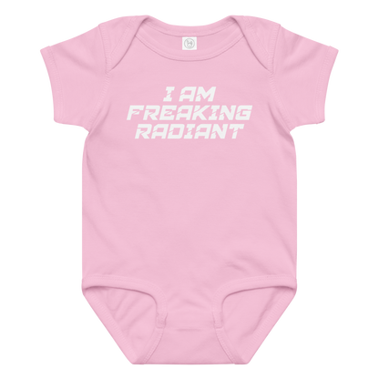"I Am Freaking Radiant" printed on a pink baby jersey bodysuit laying on a flat surface amongst other clothes