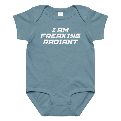 "I Am Freaking Radiant" printed on a vintage indigo baby jersey bodysuit laying on a flat surface amongst other clothes