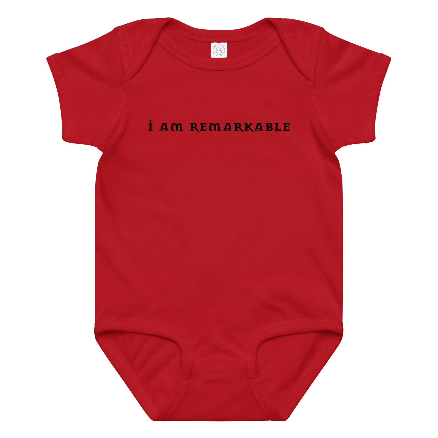 "I am remarkable" printed on a red baby jersey bodysuit laying on a flat surface amongst other clothes