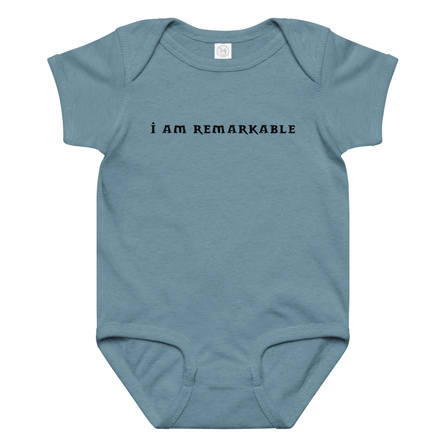 "I am remarkable" printed on a vintage indigo baby jersey bodysuit laying on a flat surface amongst other clothes