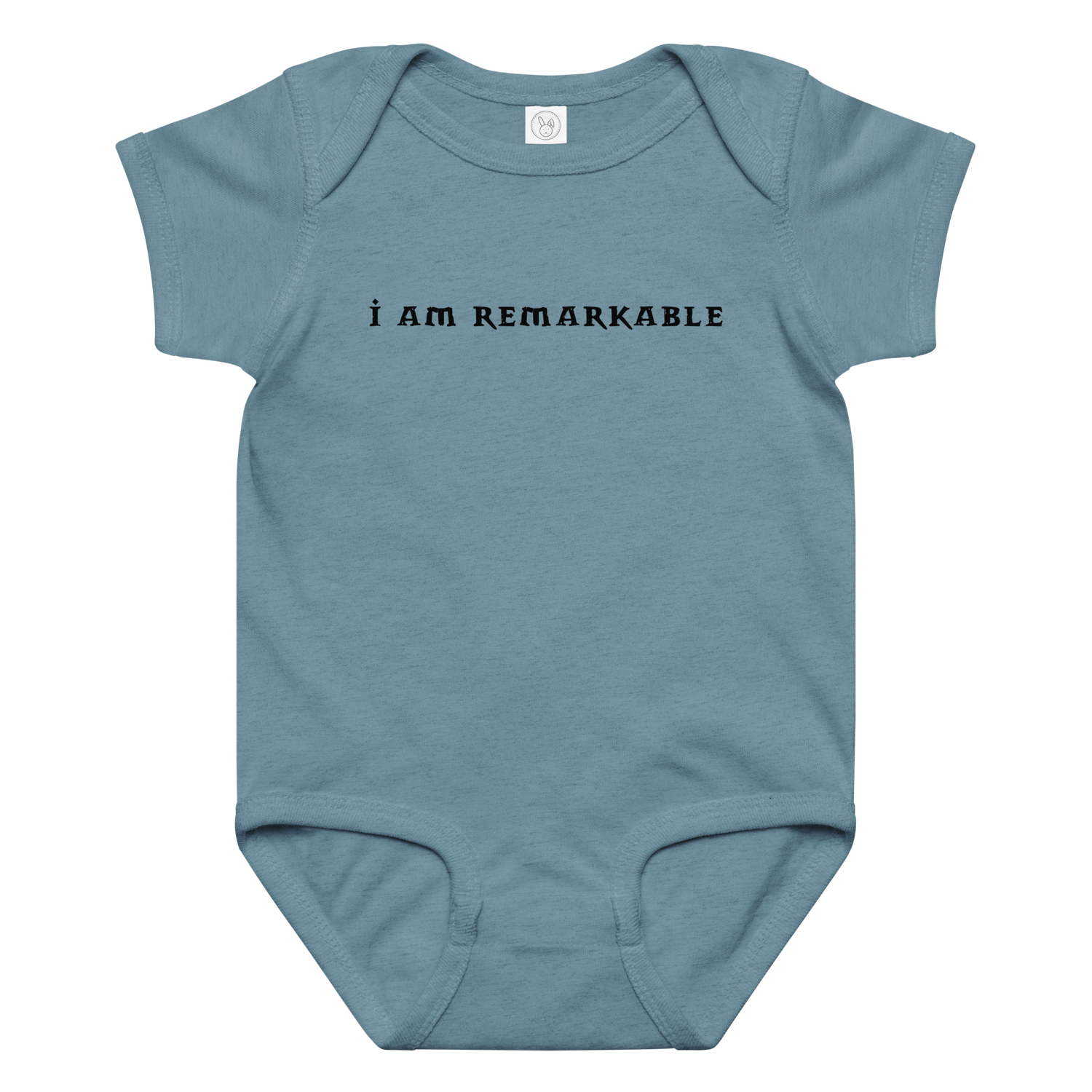 "I am remarkable" printed on a vintage indigo baby jersey bodysuit laying on a flat surface amongst other clothes