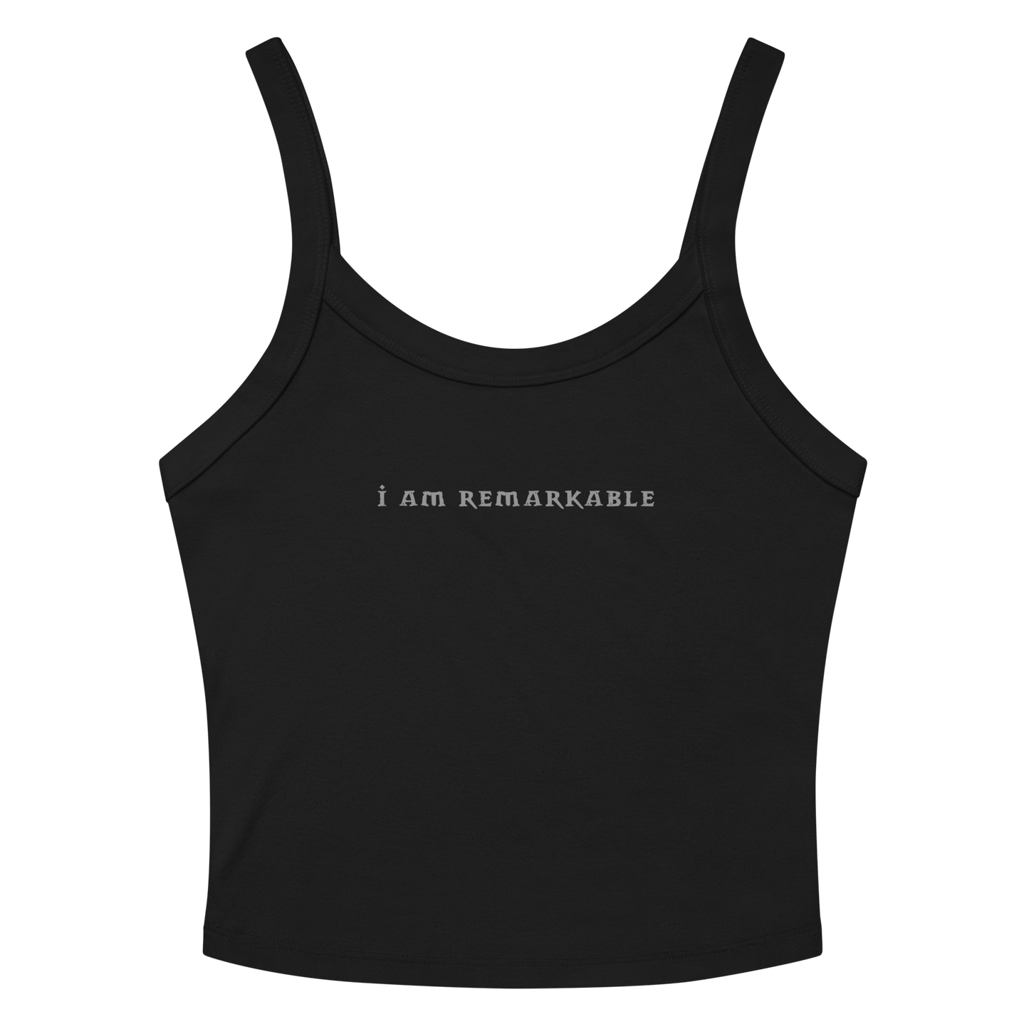 "I am remarkable" printed on a solid black blend women's micro-rib tanktop laying on a flat surface amongst sunglasses and shorts