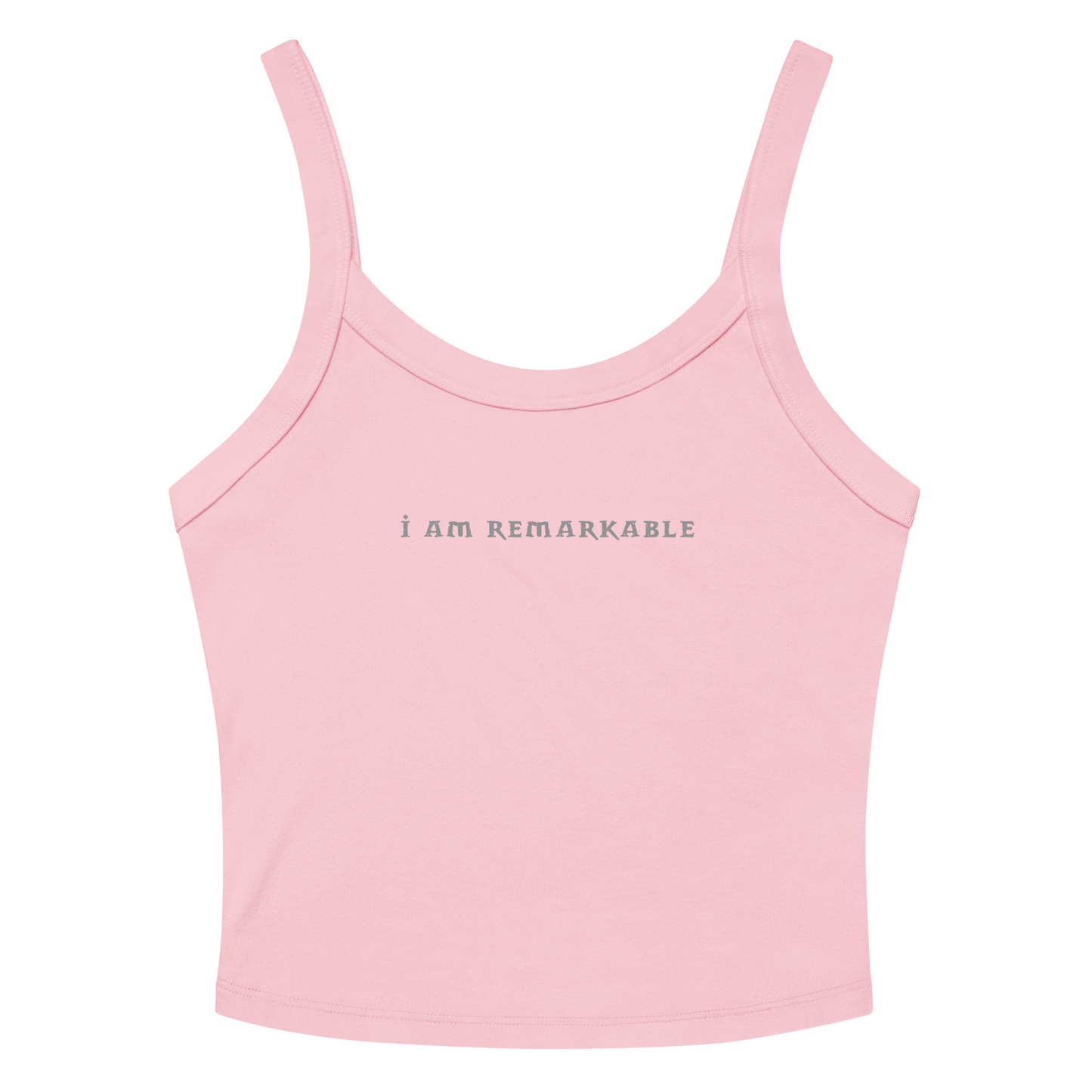 "I am remarkable" printed on a solid pink blend women's micro-rib tanktop laying on a flat surface amongst sunglasses and shorts
