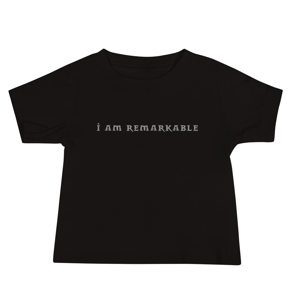 "I am remarkable" printed on a black baby jersey short sleeve tee laying on a flat surface