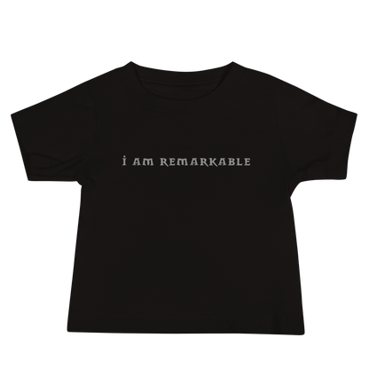 "I am remarkable" printed on a black baby jersey short sleeve tee laying on a flat surface