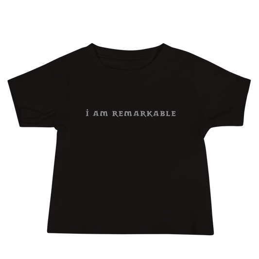"I am remarkable" printed on a black baby jersey short sleeve tee laying on a flat surface