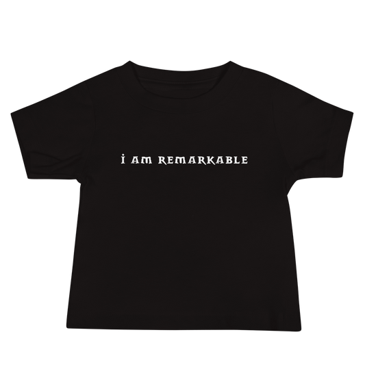 "I am remarkable" printed on a black baby jersey short sleeve tee laying on a flat surface