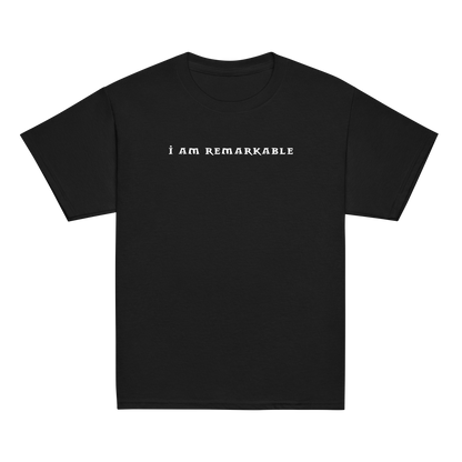 "I am remarkable" printed on a black youth classic tee laying on a flat surface