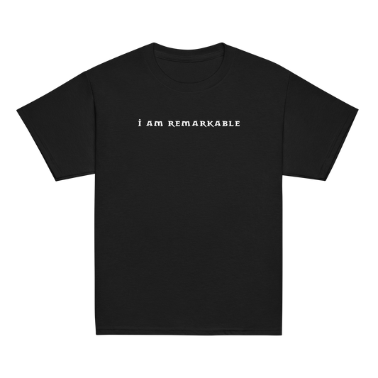 "I am remarkable" printed on a black youth classic tee laying on a flat surface