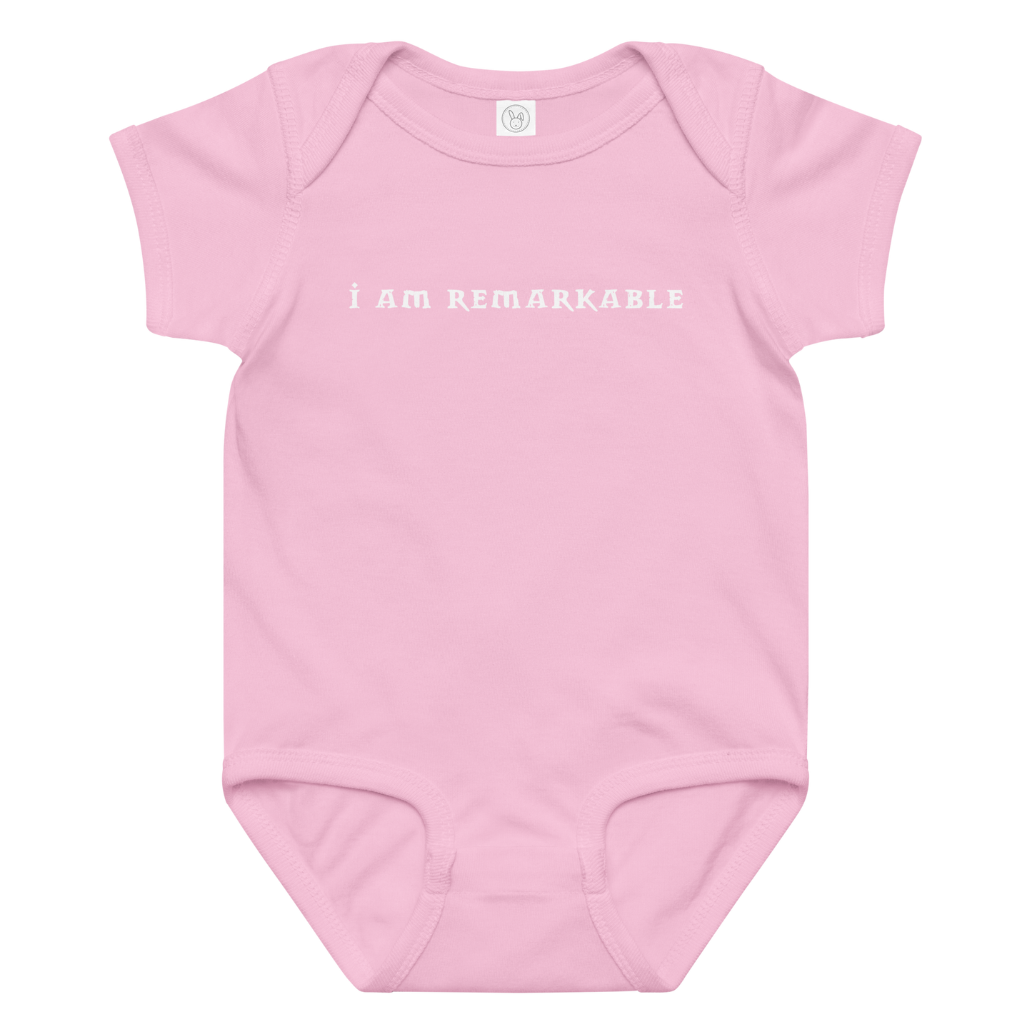 "I am remarkable" printed on a pink baby jersey bodysuit laying on a flat surface amongst other clothes