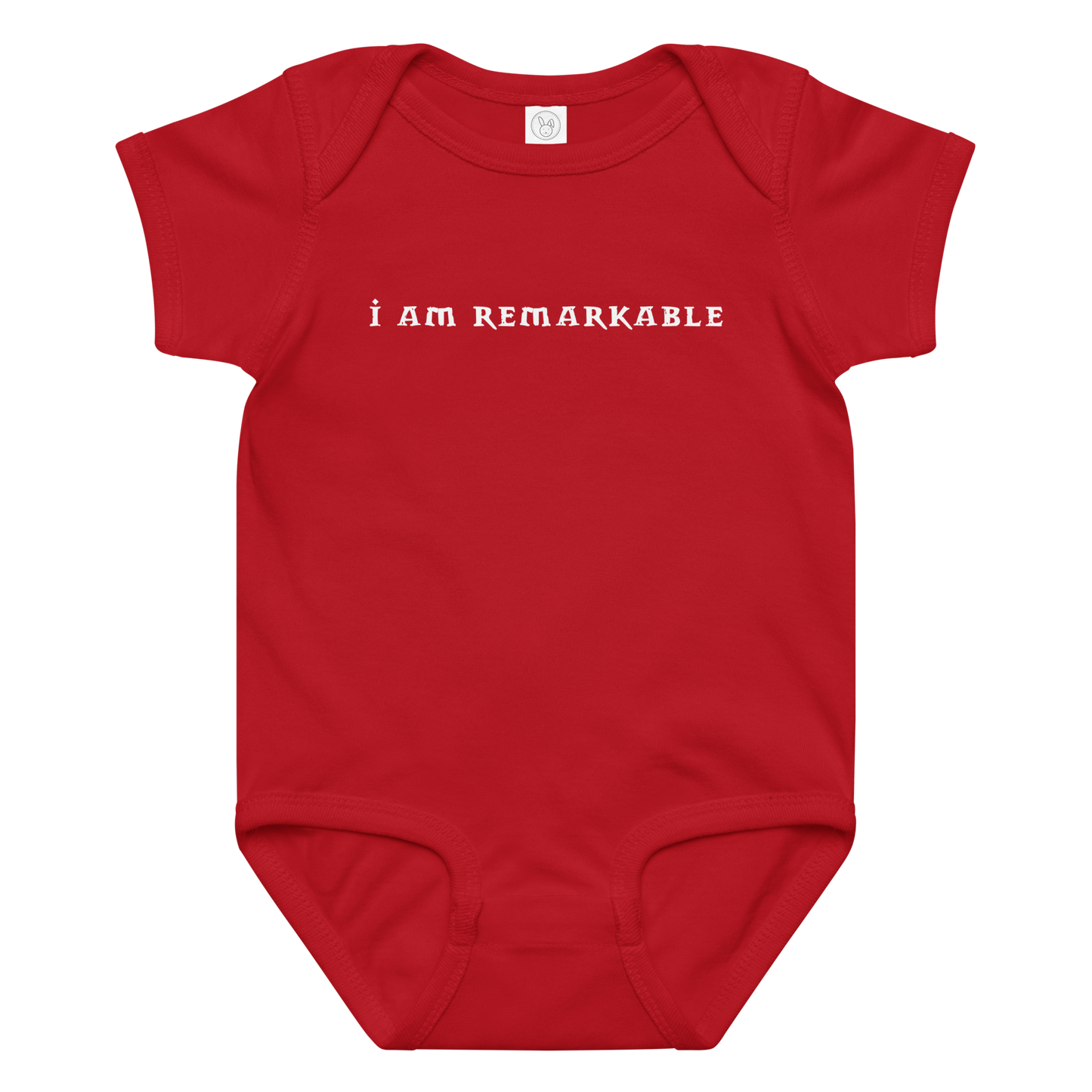 "I am remarkable" printed on a red baby jersey bodysuit laying on a flat surface amongst other clothes