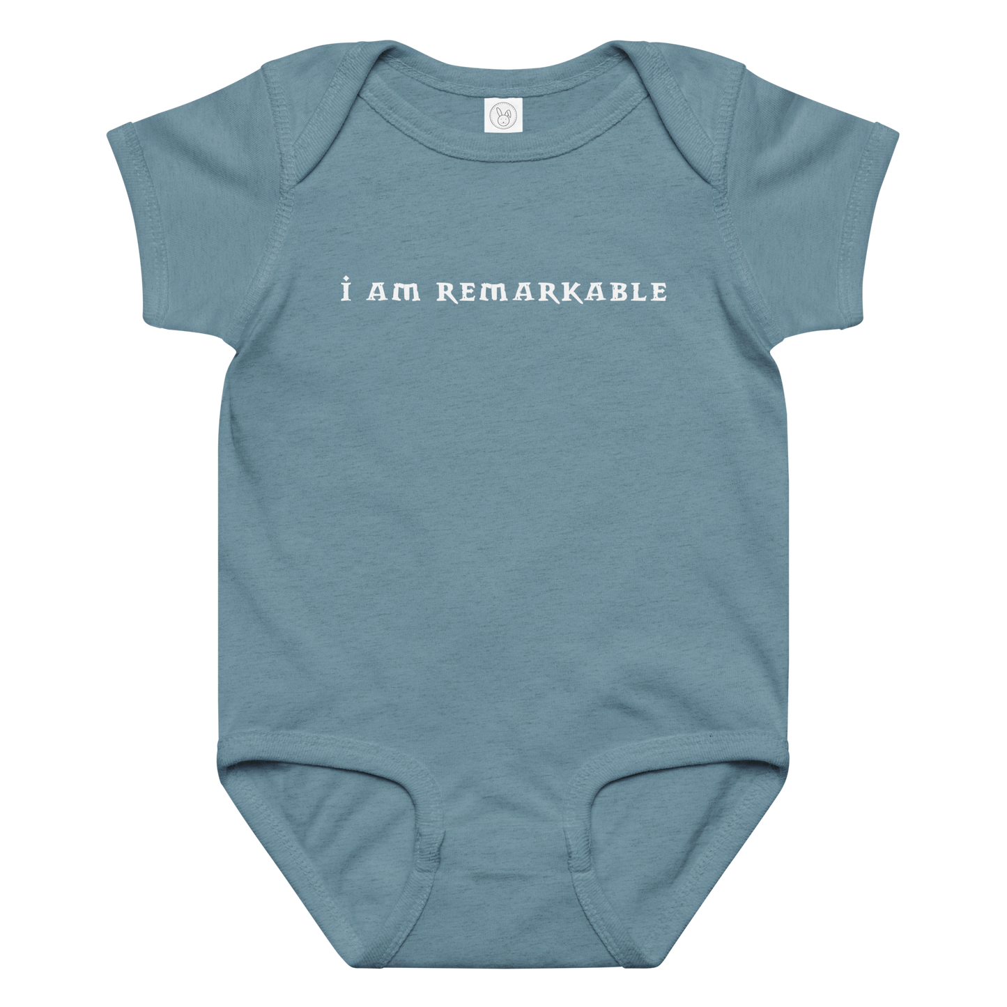 "I am remarkable" printed on a vintage indigo baby jersey bodysuit laying on a flat surface amongst other clothes