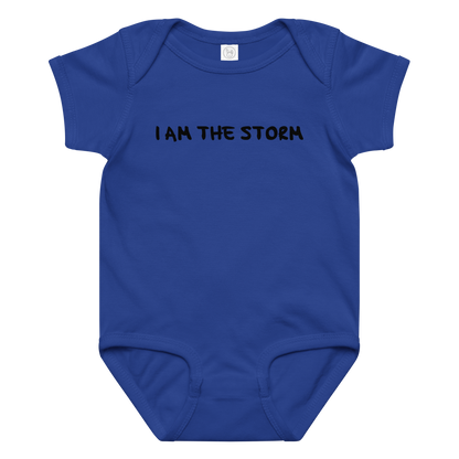 "I am the storm" printed on a royal baby jersey bodysuit laying on a flat surface amongst other clothes