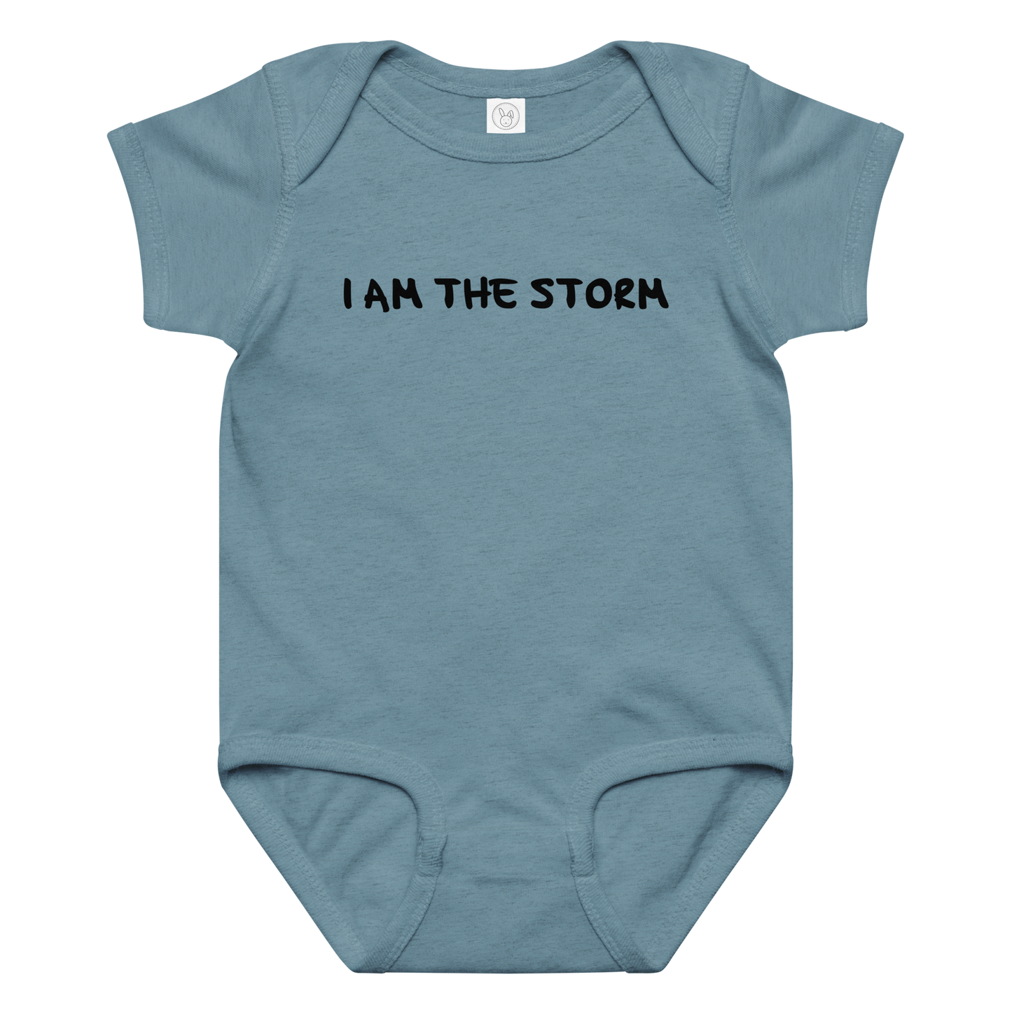 "I am the storm" printed on a vintage indigo baby jersey bodysuit laying on a flat surface amongst other clothes
