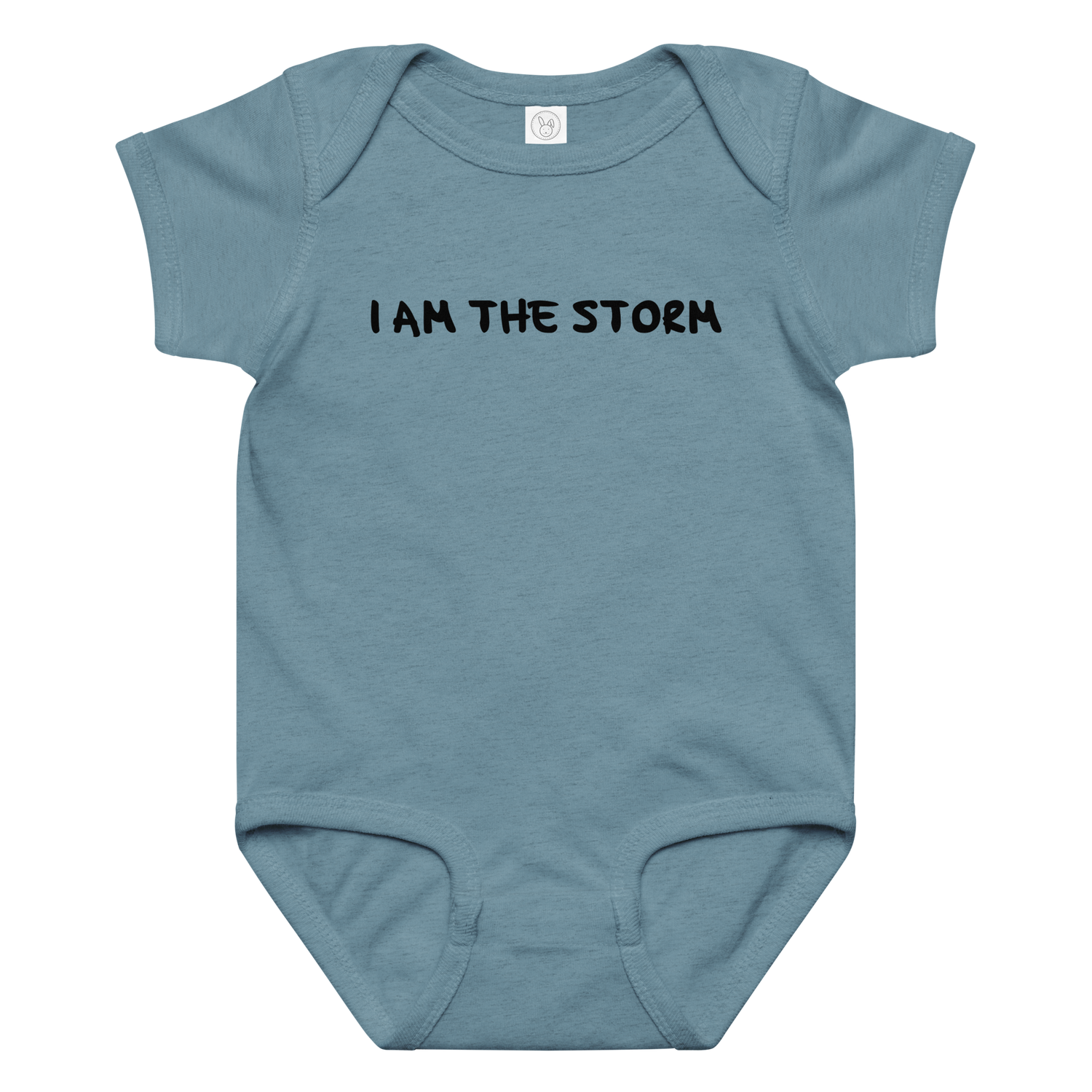 "I am the storm" printed on a vintage indigo baby jersey bodysuit laying on a flat surface amongst other clothes
