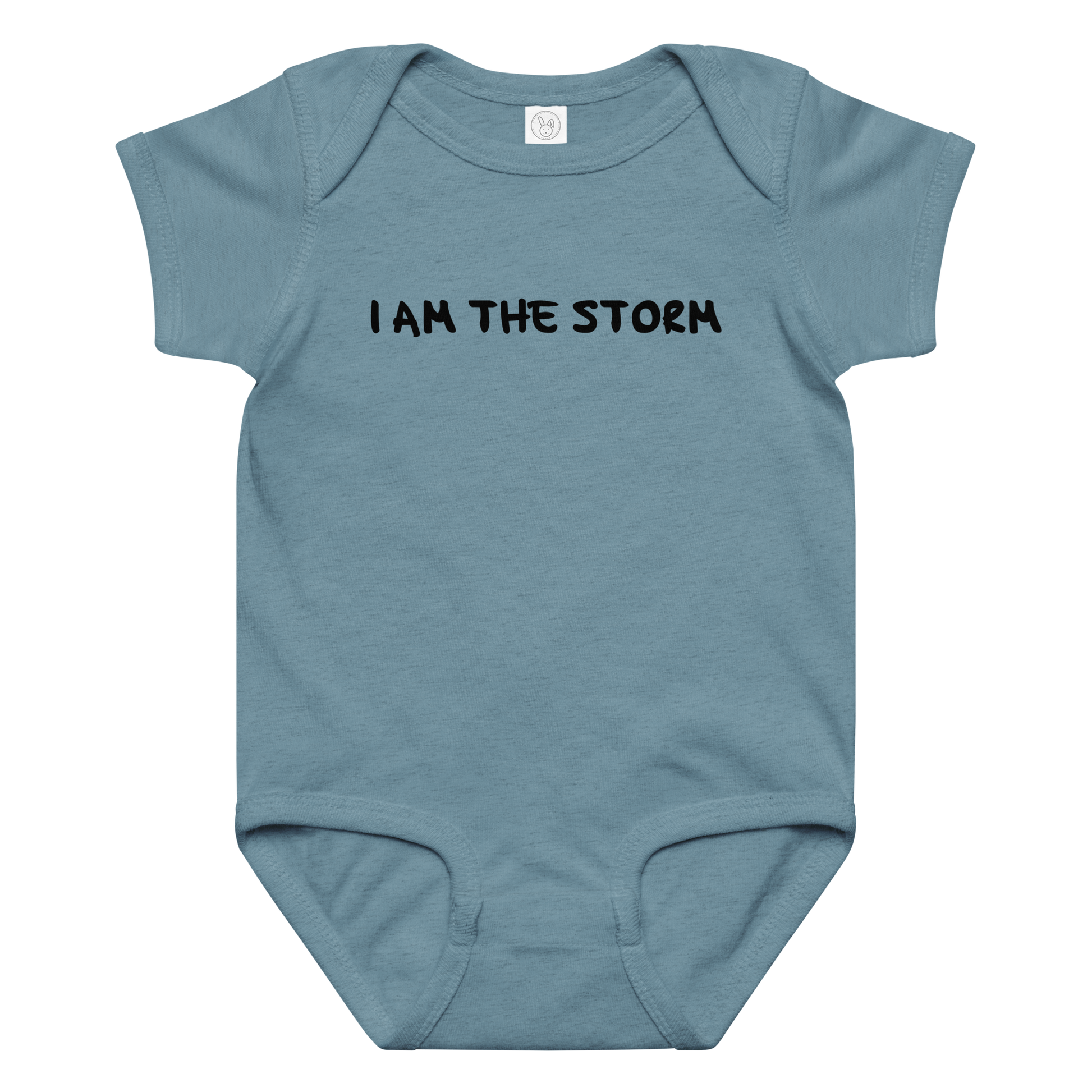 "I am the storm" printed on a vintage indigo baby jersey bodysuit laying on a flat surface amongst other clothes