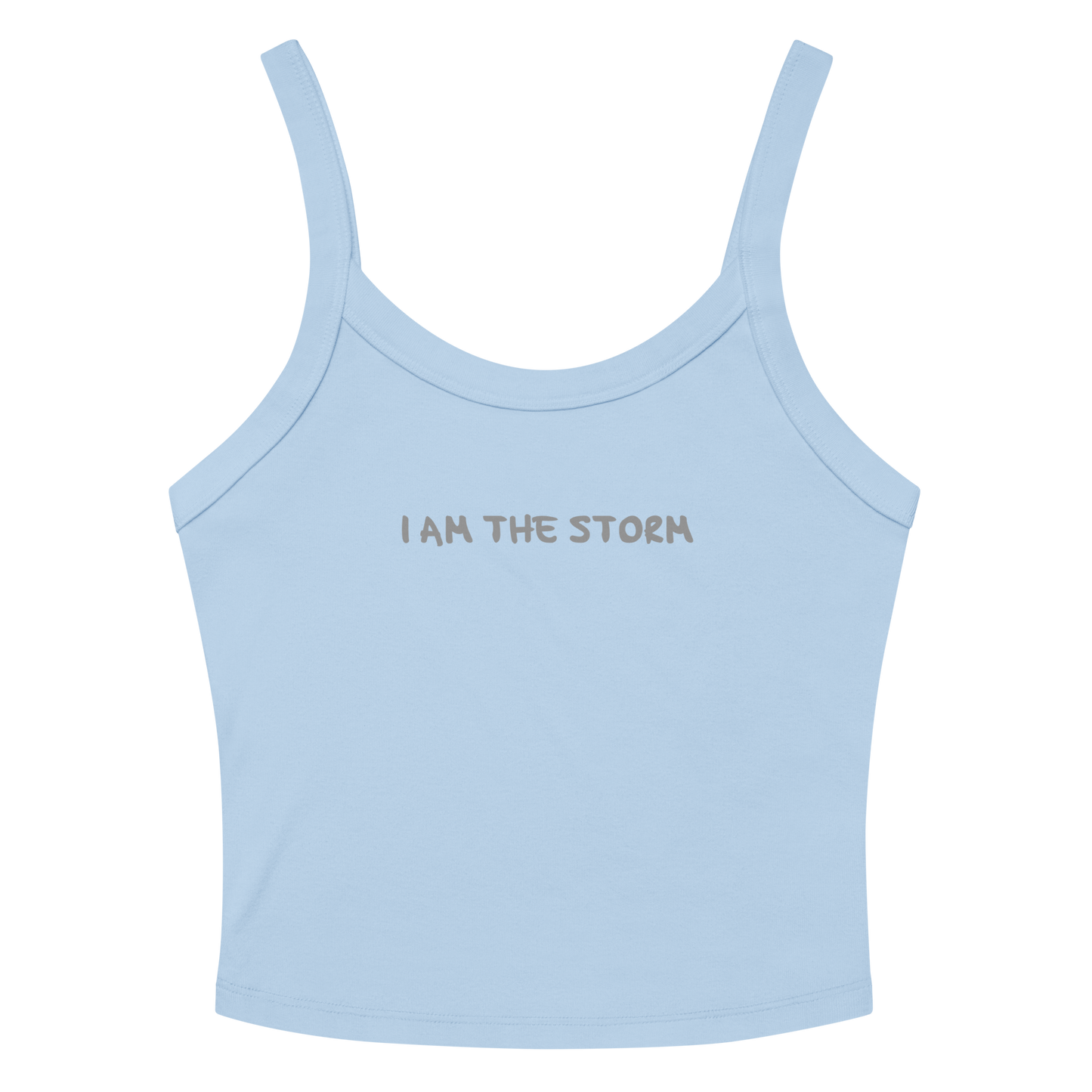 "I am the storm" printed on a solid baby blue blend women's micro-rib tanktop laying on a flat surface amongst sunglasses and shorts