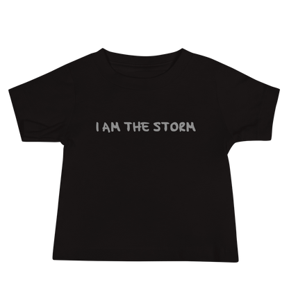 "I am the storm" printed on a black baby jersey short sleeve tee laying on a flat surface