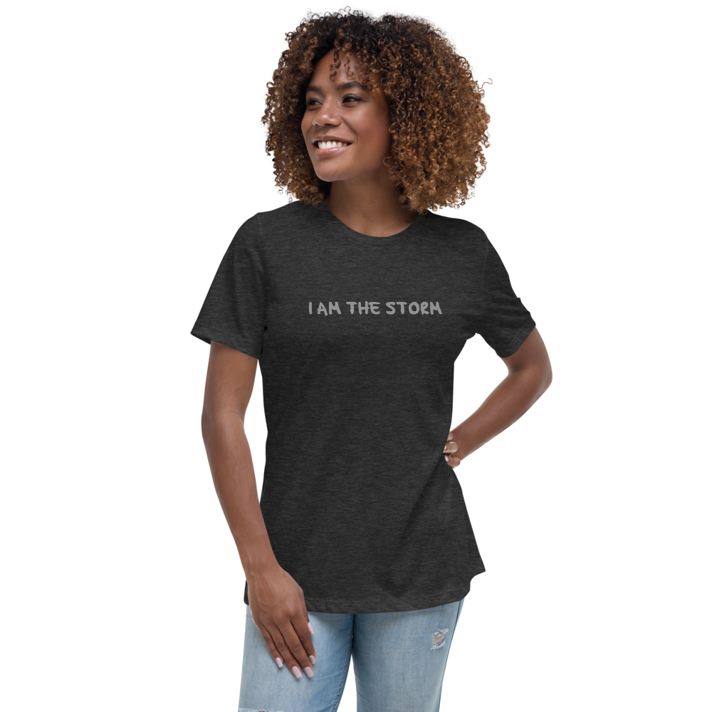 "I am the storm" printed on a dark grey heather women's relaxed t-shirt worn by a female
