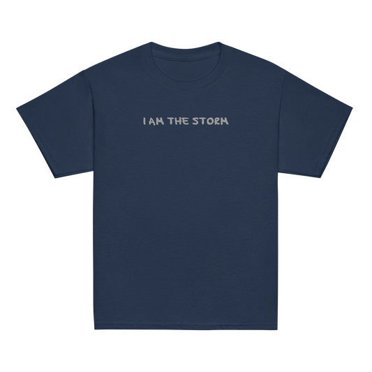 "I am the storm" printed on a navy youth classic tee laying on a flat surface