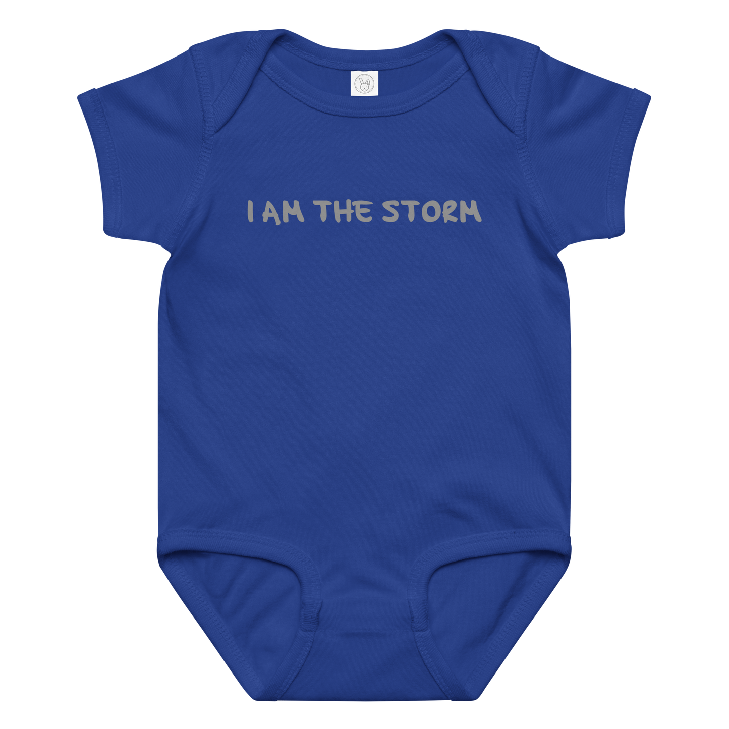 "I am the storm" printed on a royal baby jersey bodysuit laying on a flat surface amongst other clothes