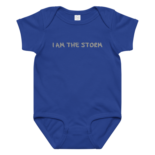 "I am the storm" printed on a royal baby jersey bodysuit laying on a flat surface amongst other clothes