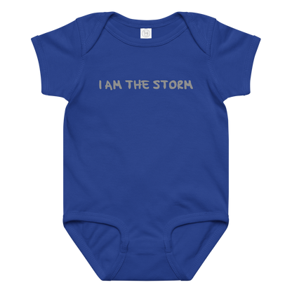 "I am the storm" printed on a royal baby jersey bodysuit laying on a flat surface amongst other clothes